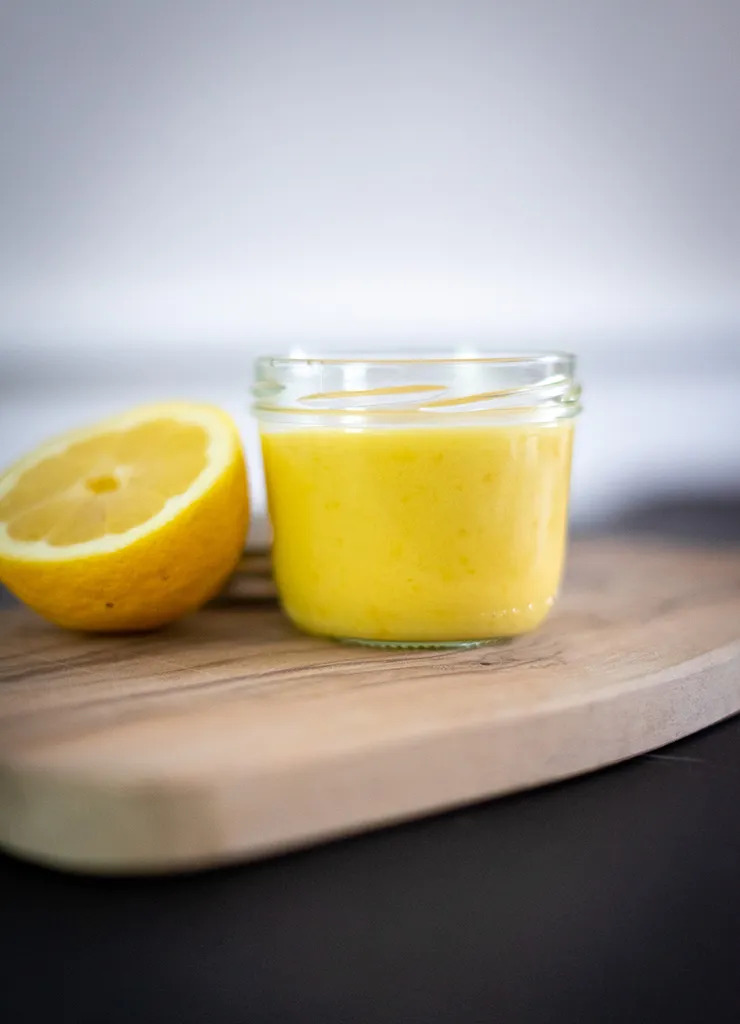 Lemon curd in een glazen pot met citroen ernaast