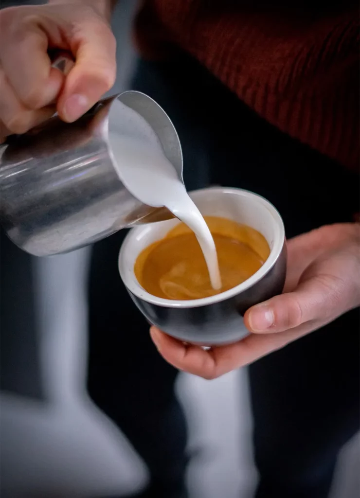 Plantaardige melk die bij een espresso gegoten word